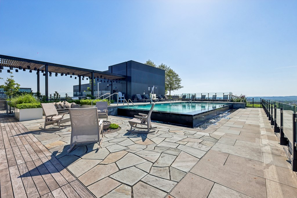 A pool area with a patio and chairs.