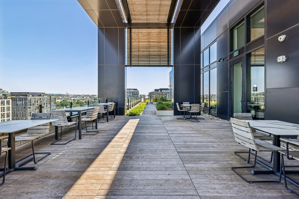 A patio with tables and chairs overlooking a cityscape.