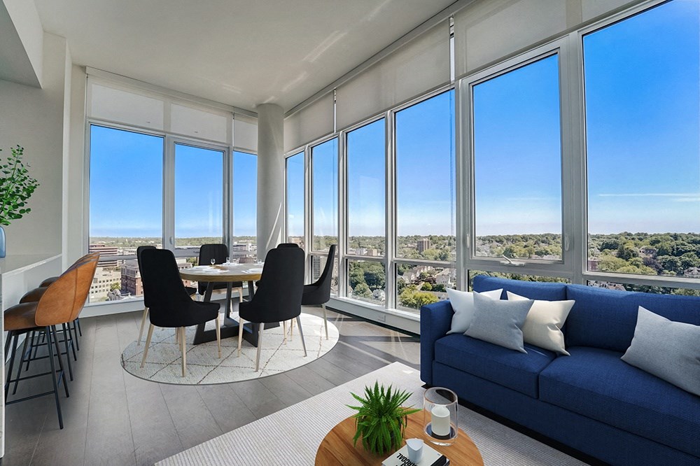 penthouse living room with a blue couch, a table with chairs and floor to ceiling windows. at Continuum, White Plains