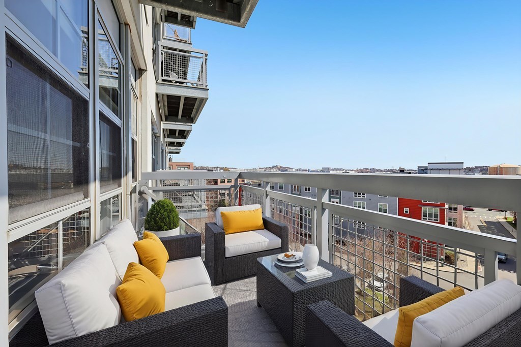 A balcony with a table and chairs overlooking a cityscape.