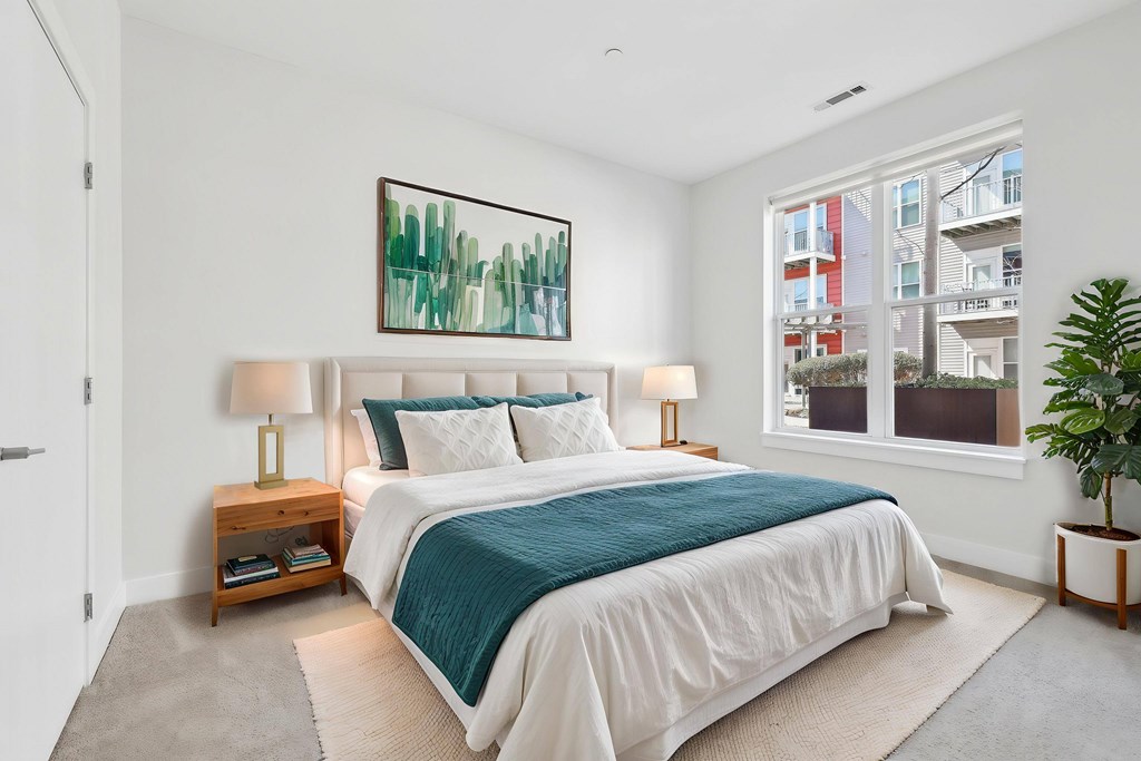 A bedroom with a large bed and a painting on the wall.