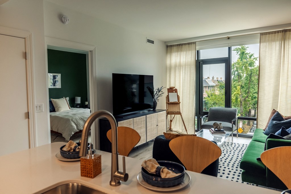 a kitchen with a sink next to a living room with a couch and a tv