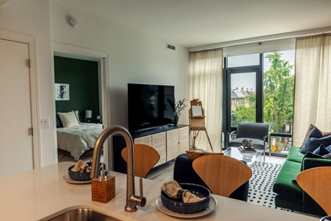 a kitchen with a sink next to a living room with a couch and a tv