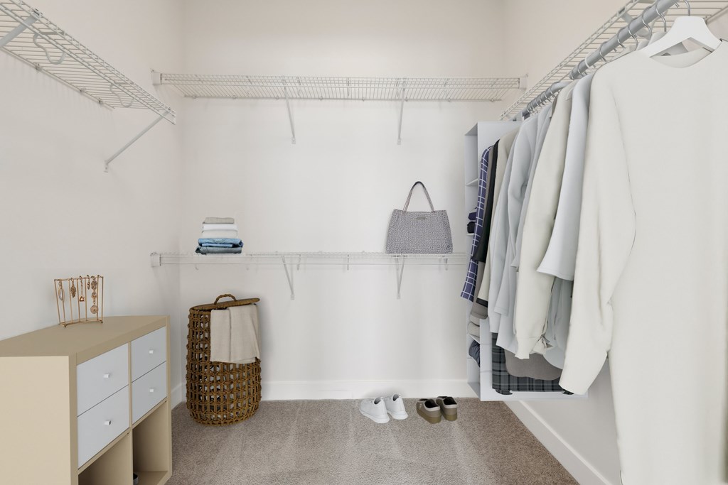 A white closet with clothes hanging and a basket on the floor.