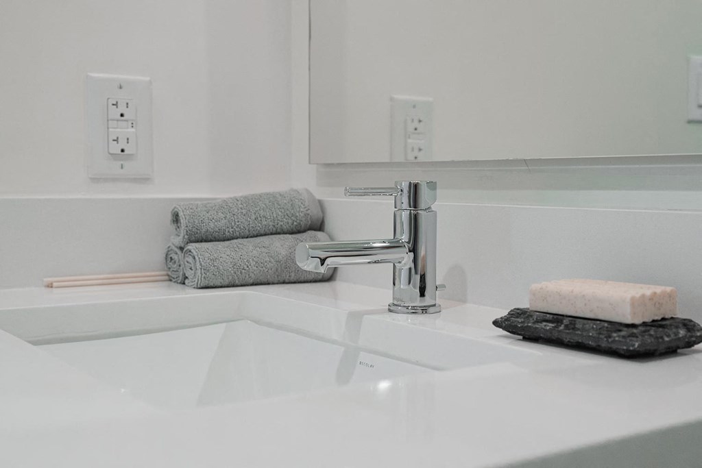 a white bathroom sink with towels and a faucet