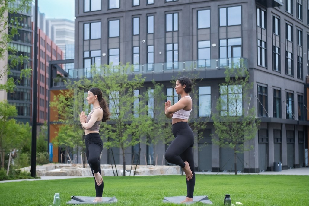 two women doing yoga in a park