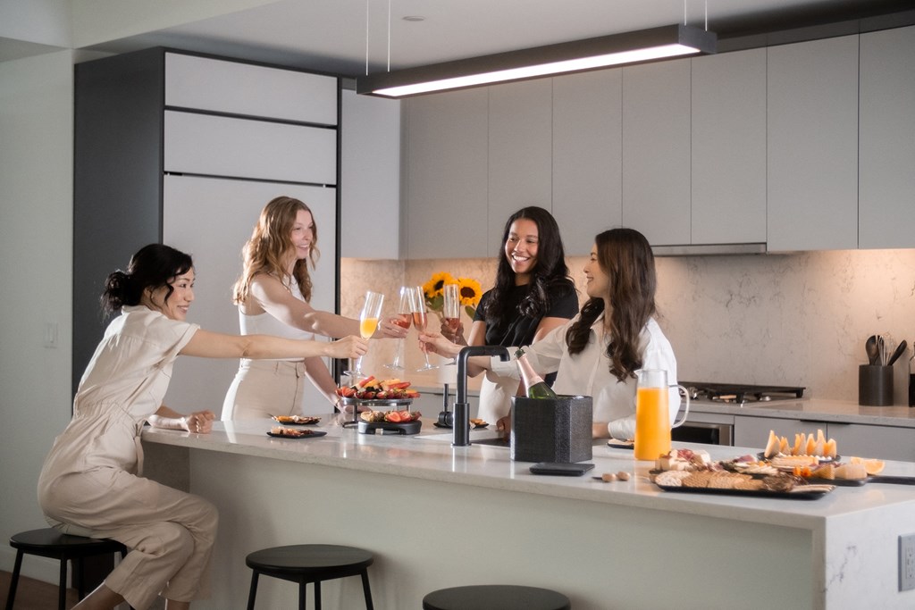 a group of women sitting around a kitchen counter eating food