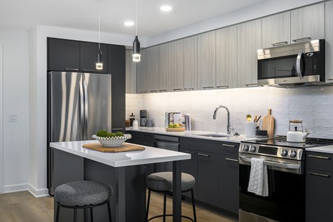 A modern kitchen with a stainless steel refrigerator and a white island.