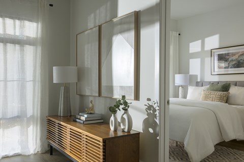 A bedroom with a bed, nightstand, and a large mirror.