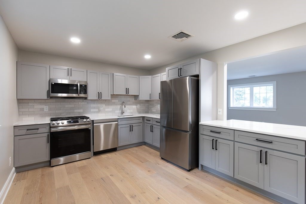 A kitchen with a refrigerator, oven, and microwave.