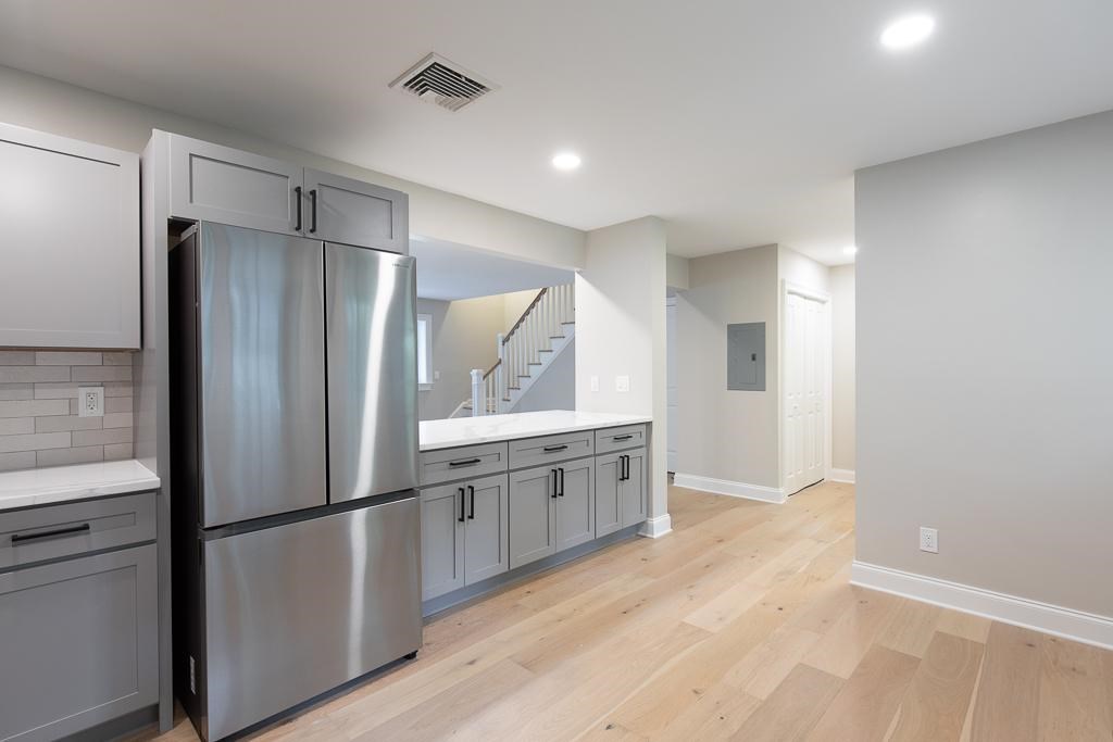 A kitchen with a stainless steel refrigerator and wooden floors.