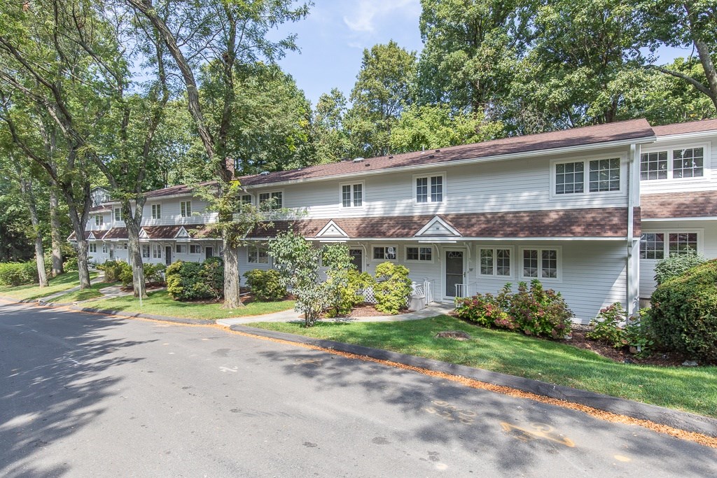 A white building with a red roof is surrounded by green trees.