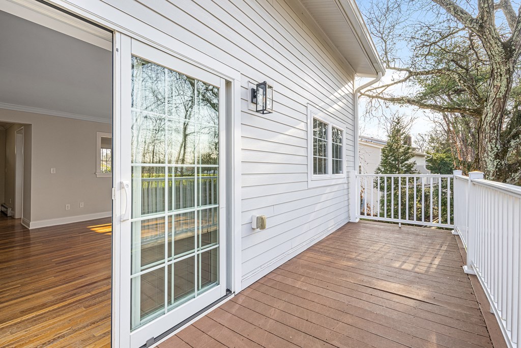 a white house with white siding and a wooden deck