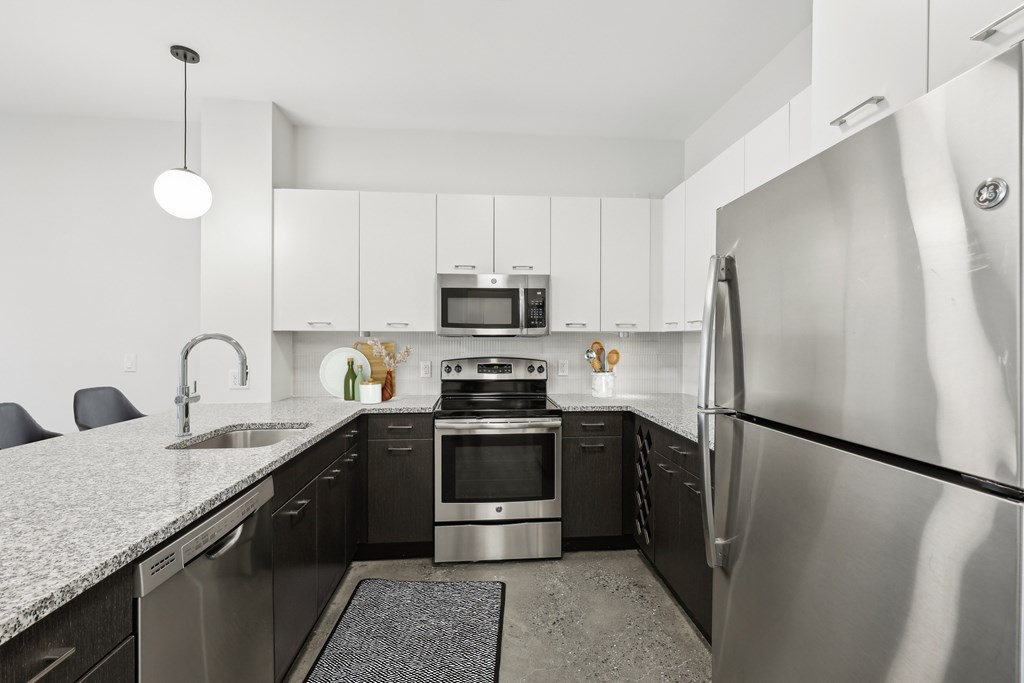 A modern kitchen with a stainless steel refrigerator and black countertops.