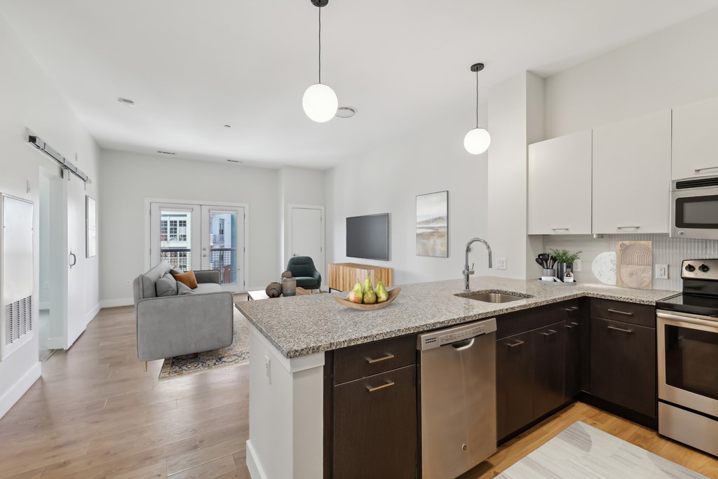 A modern kitchen with a grey sofa and wooden floors.
