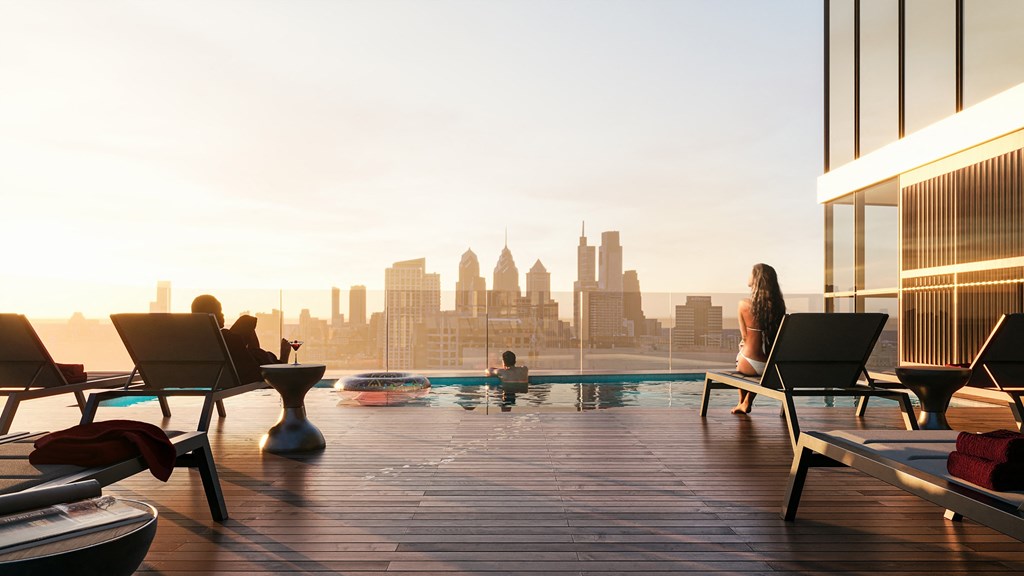 a woman sitting on a chair next to a pool with a view of a city