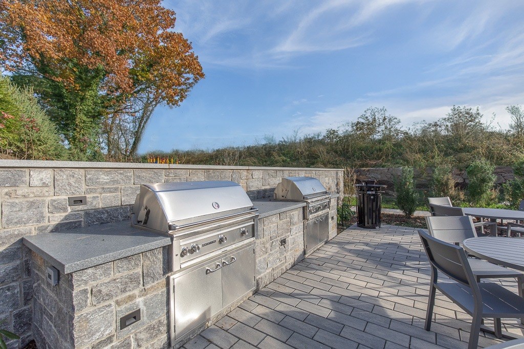 A stone wall with a grill and a table in front of it.