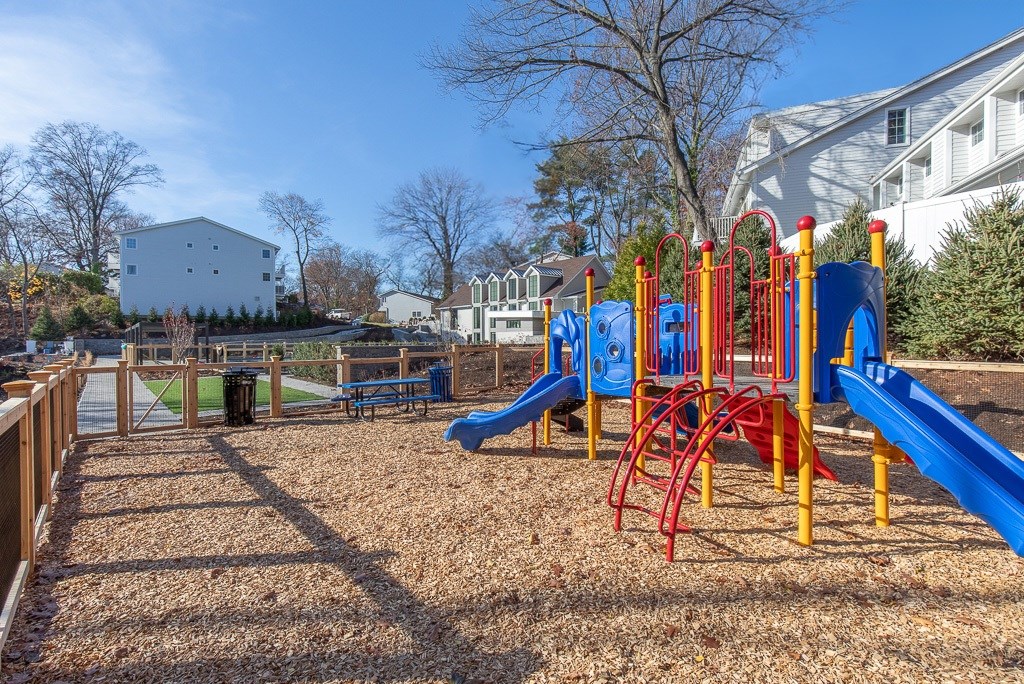 A playground with a blue slide and red and yellow swings.