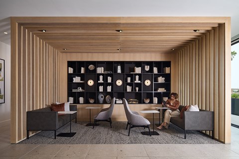 a woman sits at a table in front of a large bookshelf