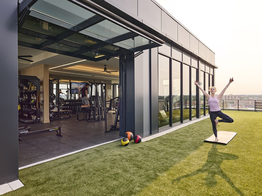 a woman doing a yoga pose on a yoga mat on a lawn in front of a building