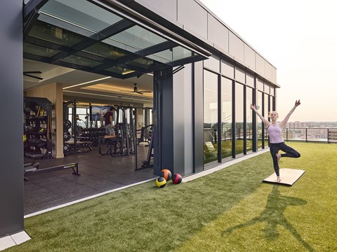 a woman doing a yoga pose on a yoga mat on a lawn in front of a building