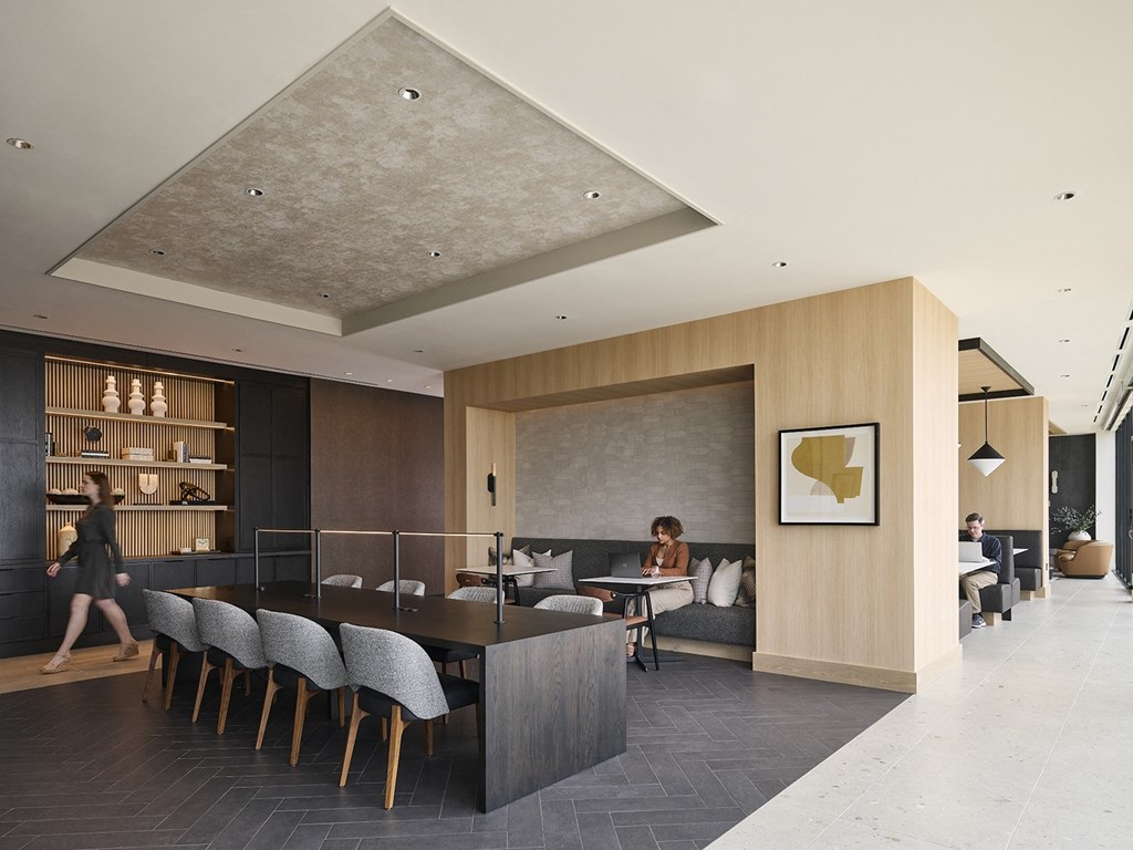 a rendering of the lobby of the hotel with a long black table and chairs and a woman