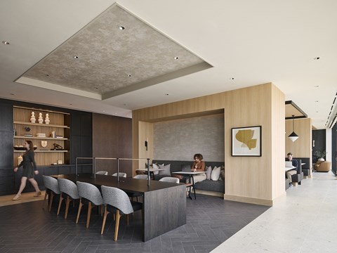 a rendering of the lobby of the hotel with a long black table and chairs and a woman