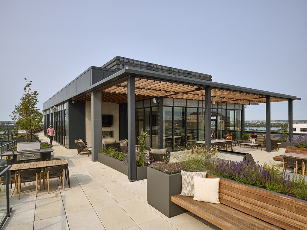 a view of the rooftop patio of a building with a pergola and tables and chairs