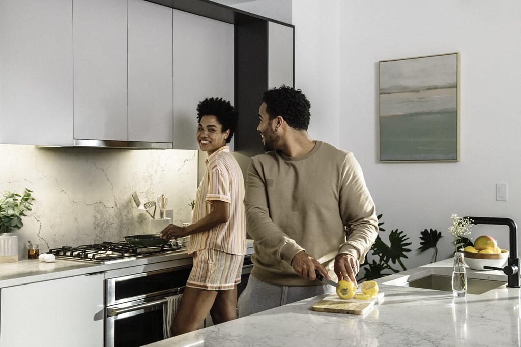 a man and a woman in a kitchen chopping fruit on a cutting board