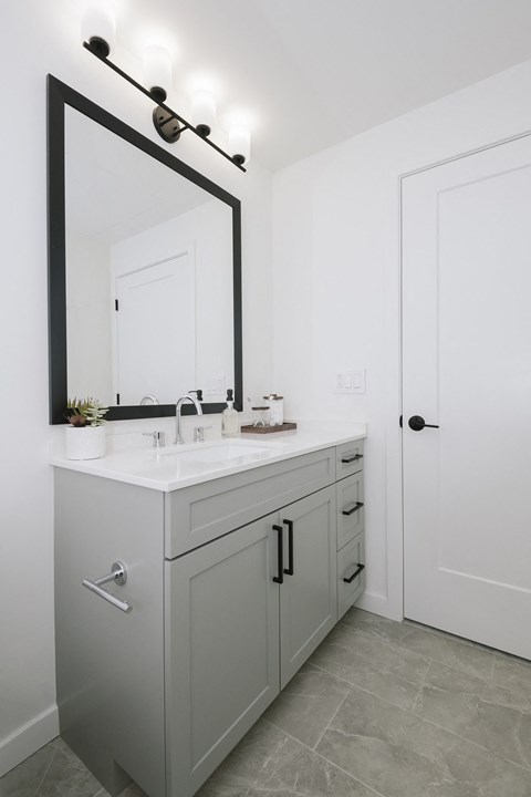 a white bathroom with a white sink and a mirror