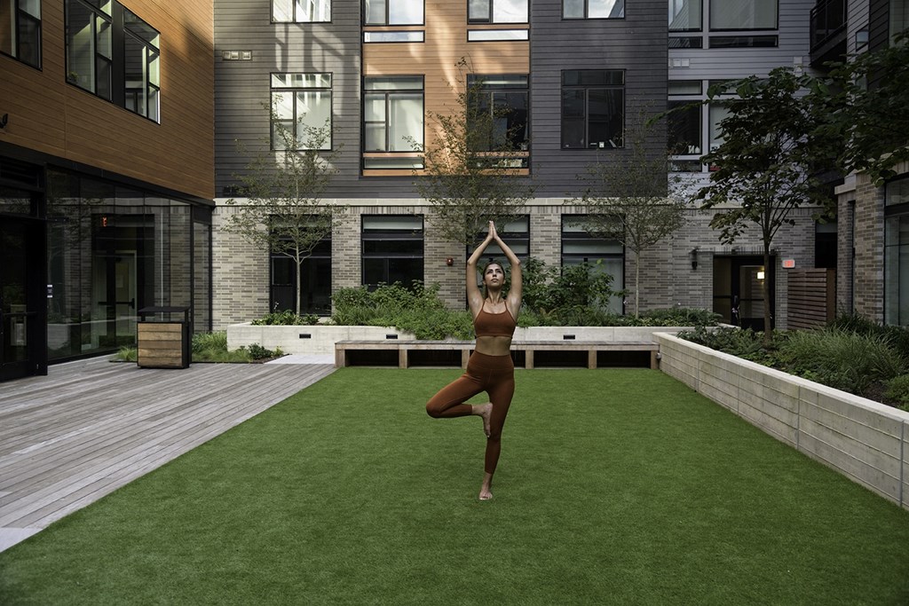 A woman in a yoga pose on a green lawn in front of a building at Arrowwood Apartments, North Bethesda