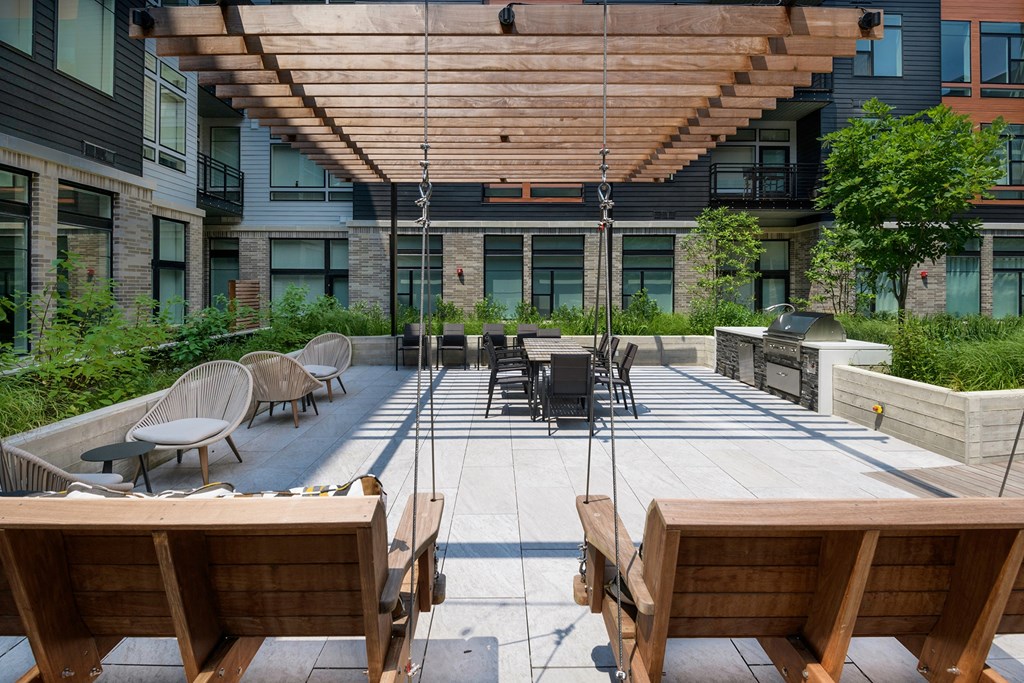 Outdoor patio with swings, lounge chairs, and grills at Arrowwood Apartments, North Bethesda