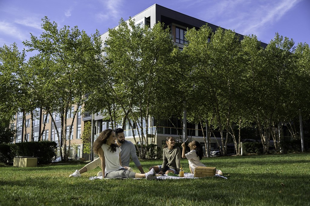 A group of people are sitting on the grass in front of a building at Arrowwood Apartments, North Bethesda