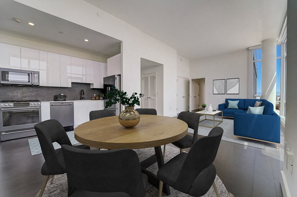 penthouse living room and kitchen with a blue couch and a wooden table with a vase with  at Continuum, New York, 10606