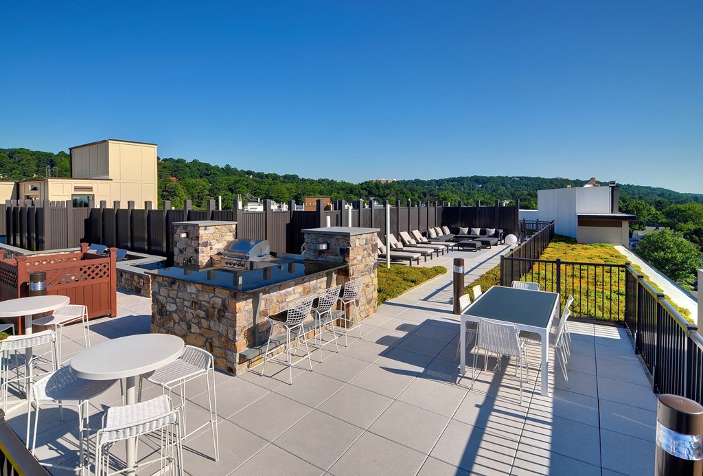 a rooftop patio with tables and chairs and a building in the background at Valley and Bloom, Montclair, 07042