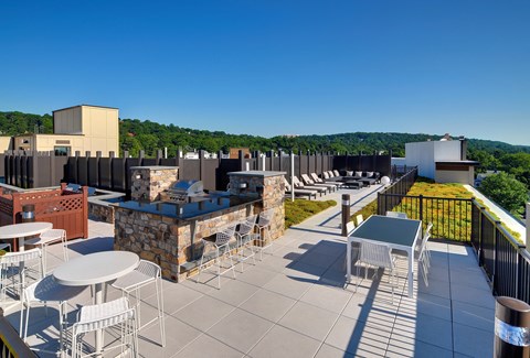 a rooftop patio with tables and chairs and a building in the background at Valley and Bloom, Montclair, 07042
