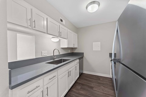 A kitchen with white cabinets and a stainless steel refrigerator.