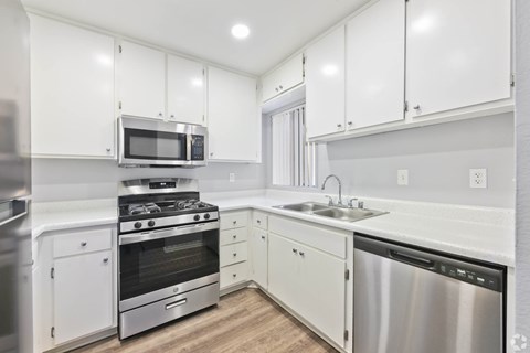 A modern kitchen with white cabinets and stainless steel appliances.