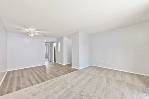 A spacious room with a carpeted floor and a ceiling fan.