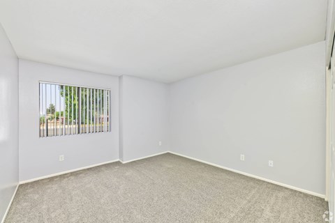 A room with a window and a carpeted floor.