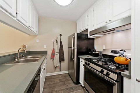 A kitchen with a black refrigerator and a black stove top oven.