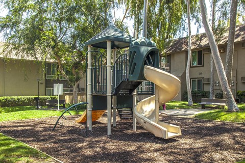 A playground with a green slide and a yellow slide.