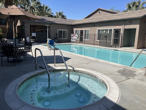 a swimming pool in the courtyard of a house with a pool and patio with chairs