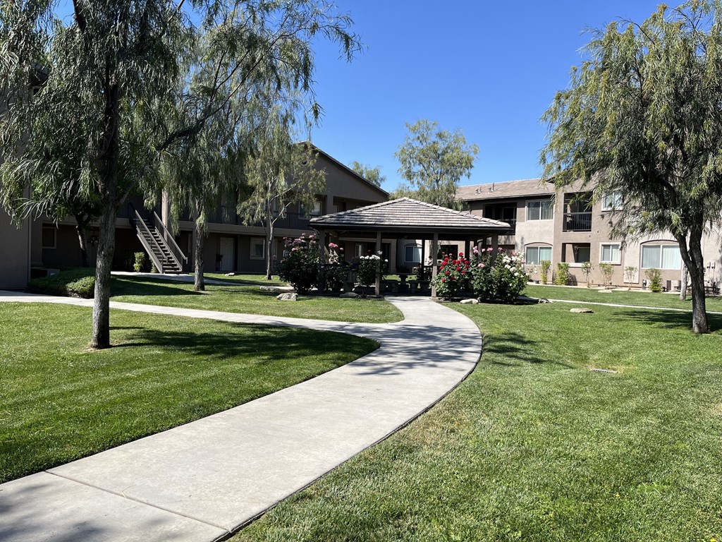 a sidewalk leading to a gazebo in front of an apartment building