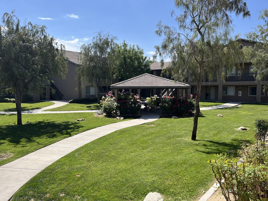 a gazebo sits in the middle of a grassy area with trees