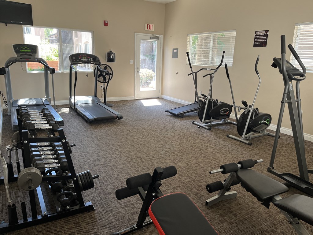 a gym with cardio machines and weights on the floor