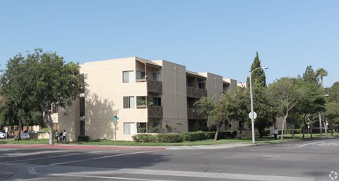 A building with a grey facade is surrounded by trees and bushes.