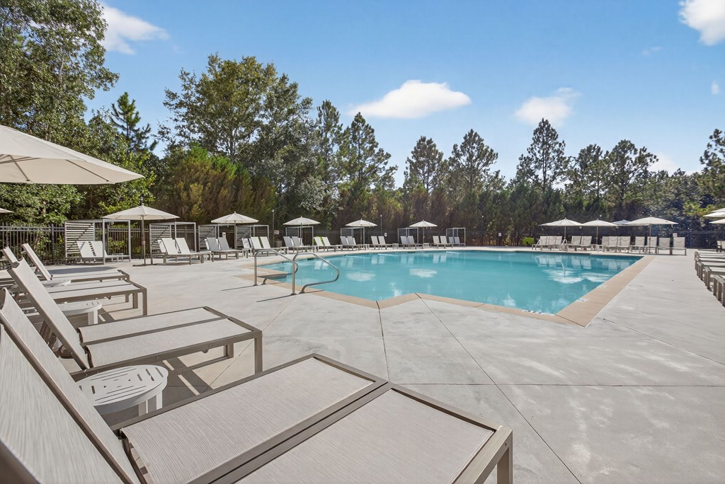 A large outdoor swimming pool surrounded by sun loungers and umbrellas.