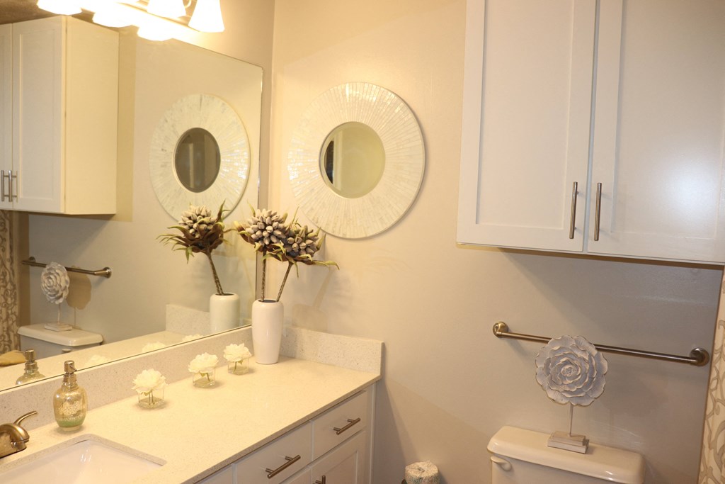 a bathroom with two mirrors and a sink and a toilet  at Laurelwood Apartment Homes, Mississippi, 39440
