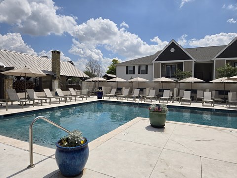 A pool area with a blue pot in the foreground and a building in the background.